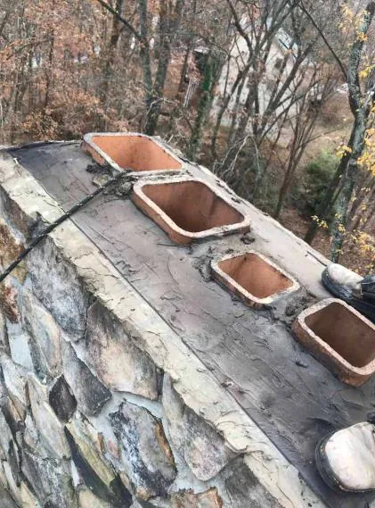 A stone chimney crown with clay flue tiles and fresh masonry crown work