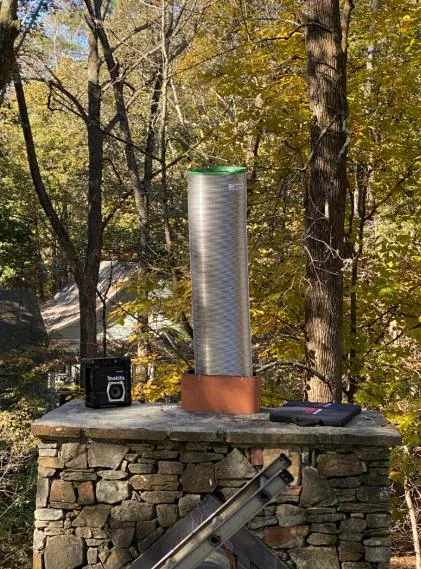 A stainless-steel chimney liner and copper collar installed on a stone chimney crown